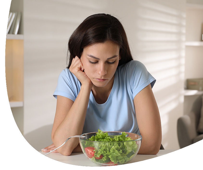 Woman looking her salad nostalgic